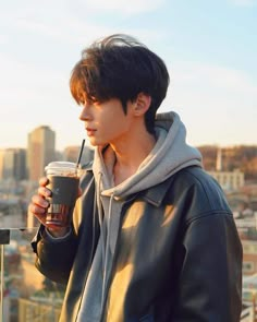 a young man holding a coffee cup in his right hand and looking off into the distance