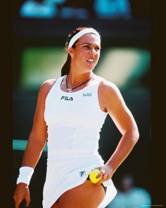 a woman holding a tennis racquet on top of a tennis court with a ball in her hand