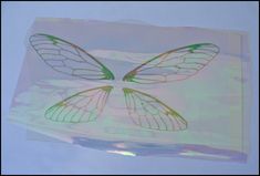 two butterfly wings are drawn on a piece of clear paper with green and yellow ink