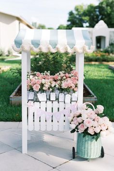 a white bench with pink flowers on it and a blue striped awning over it