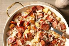 a pan filled with sausage and potatoes on top of a wooden table