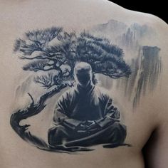 a man with a tattoo on his back is sitting in front of a bonsai tree