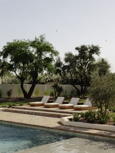 an outdoor swimming pool with lounge chairs and trees