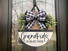 a sign that says grandkids spoiled here hanging on the front door with a bow