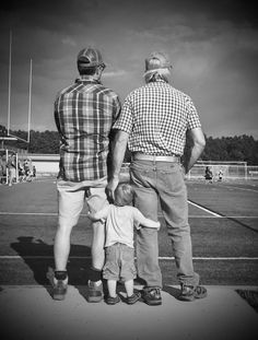 an older man and two younger men holding hands with a young child on a tennis court