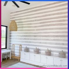 a room with striped wallpaper and white cabinets