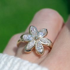 a close up of a person's hand with a flower ring on their finger