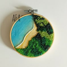 an embroidery art piece with the words afa on it and a beach in the background