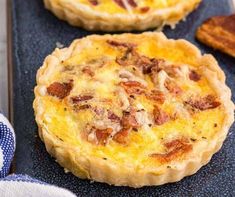 two quiche pies sitting on top of a baking sheet