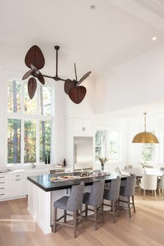 a large kitchen with white cabinets and an island in the middle is surrounded by gray chairs