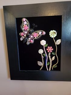 a black frame with some flowers and a butterfly on it