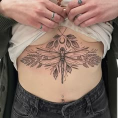 a woman with a dragonfly tattoo on her stomach