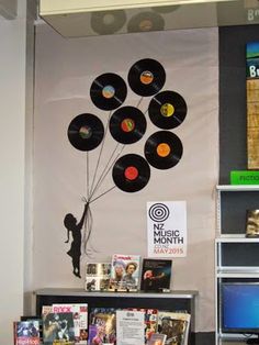 there is a display with vinyl records on the wall and an image of a person holding a balloon