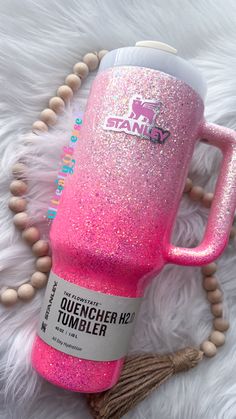 the pink glitter tumbler is next to a tassell with beads on it