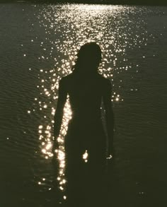 a woman standing in the water at sunset