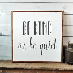 a sign that says be kind or be quiet on the shelf next to a potted plant