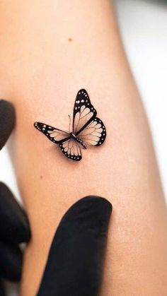 a woman's arm with a small butterfly tattoo on the left side of her arm