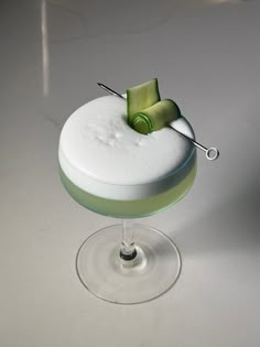 a green and white dessert sitting on top of a wine glass next to a knife