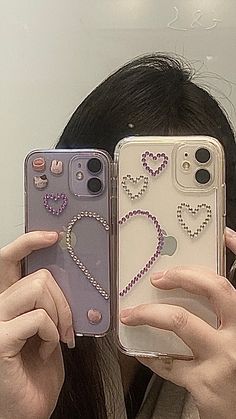 two women holding up their cell phones with hearts on the back and pearls attached to them