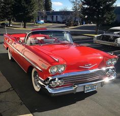 an old red car parked in a parking lot