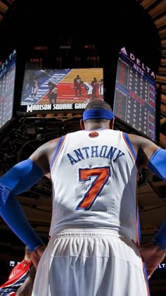 a basketball player is standing in front of the scoreboard with his hands on his hips