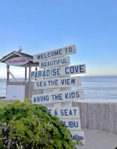 a sign that is on the side of a beach next to the ocean with words written all over it