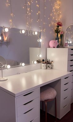 a white vanity with lights hanging from it's sides and a stool in front of it