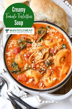 a bowl of creamy tomato tortellini soup on a white plate with bread in the background