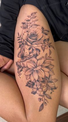 a woman's thigh with flowers and leaves tattoo on her leg, sitting on the floor