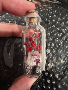 someone is holding a bottle with flowers in it