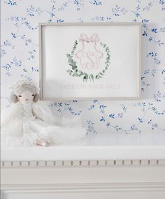 a white teddy bear sitting on top of a bed next to a framed picture and wallpaper