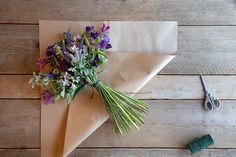 a bunch of flowers sitting on top of a piece of brown paper next to scissors