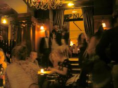 a group of people sitting at tables in a room with chandeliers and lights