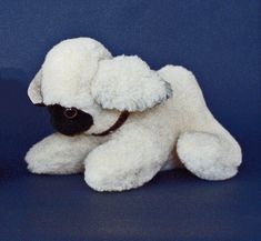 a white stuffed dog sitting on top of a blue floor