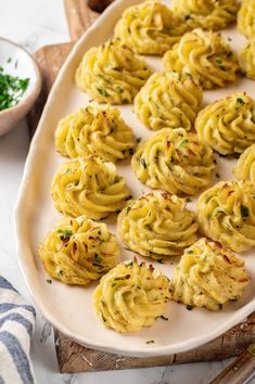 some food is on a white plate and next to a bowl with parsley sprinkles