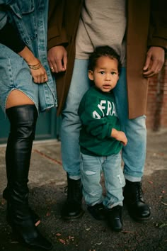 a little boy standing next to his parents legs