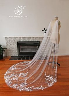 a wedding veil with white flowers is on display in front of a fire place and fireplace