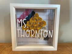 a white frame with some paper flowers in it