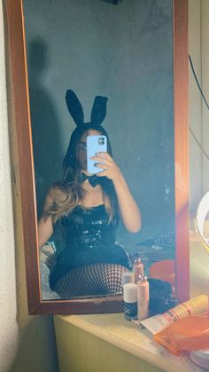 a woman taking a selfie in front of a mirror with bunny ears on her head