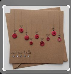 some red buttons are attached to brown cards with words deck the balls on them and hang from strings