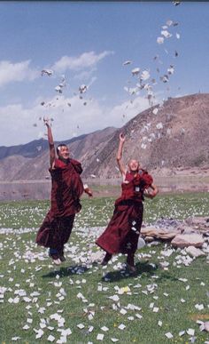 two people in red robes are throwing confetti into the air with their hands