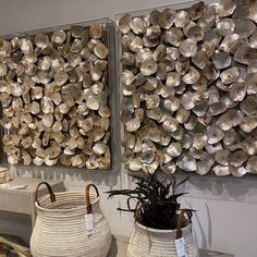 two baskets sitting on top of a table next to each other near metal wall art