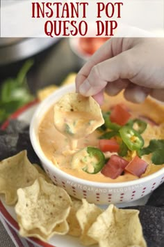 a hand dipping tortilla chips into a bowl of queso dip