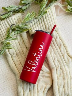 a red tumbler sitting on top of a white sweater