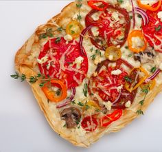 a pizza topped with lots of veggies on top of a white tablecloth