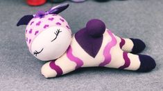 a purple and white stuffed animal laying on top of a gray floor next to other toys