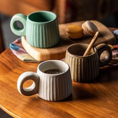 two mugs sitting on top of a wooden table next to cookies and other items