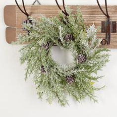 a wreath is hanging on a coat rack with two coats and one pair of skis