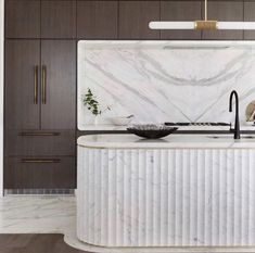 a kitchen with marble counter tops and wooden cabinetry, along with an island in the middle