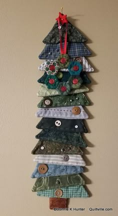 a christmas tree made out of different types of fabric and buttons on a wall hanging ornament